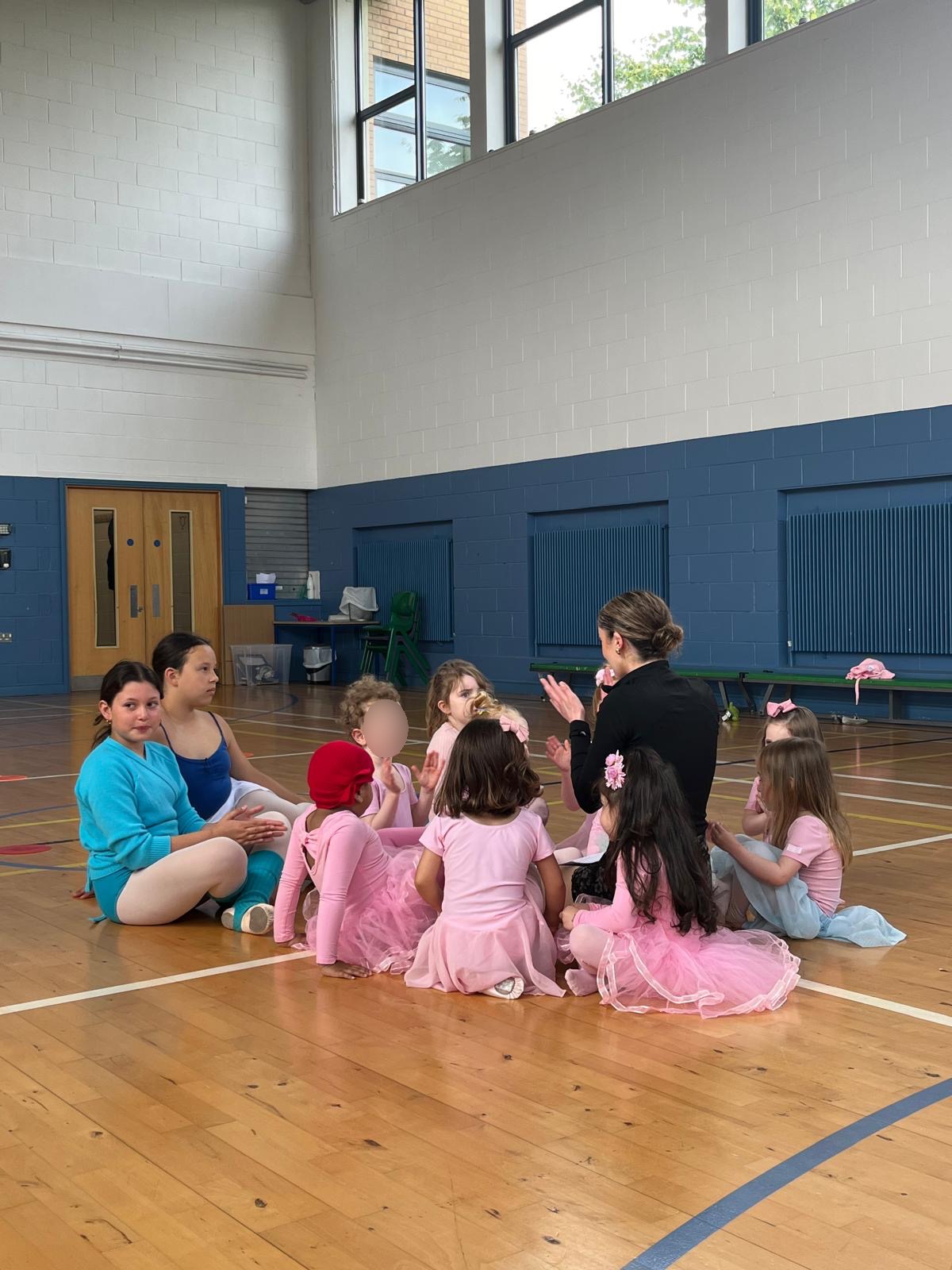 Ballet teacher with young dancers in a circle